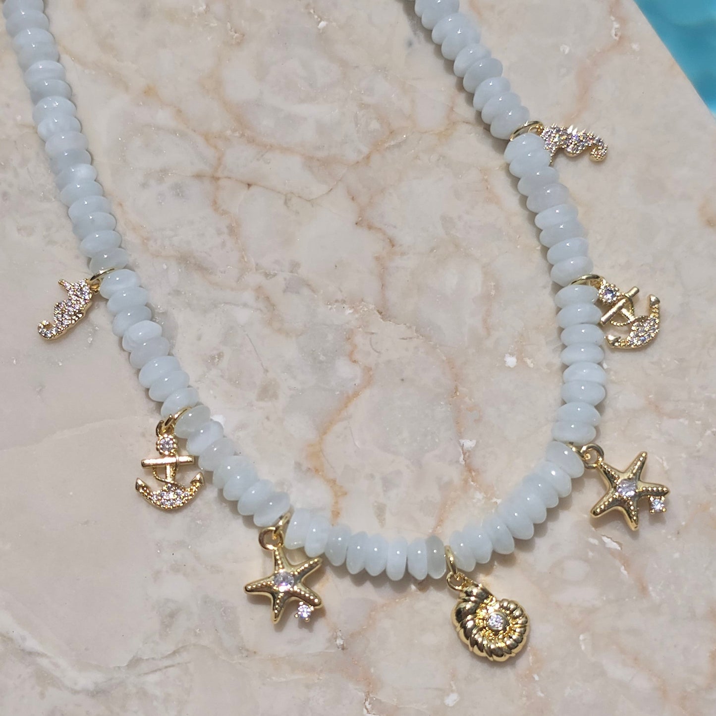 Necklace with gold charms on a marble surface