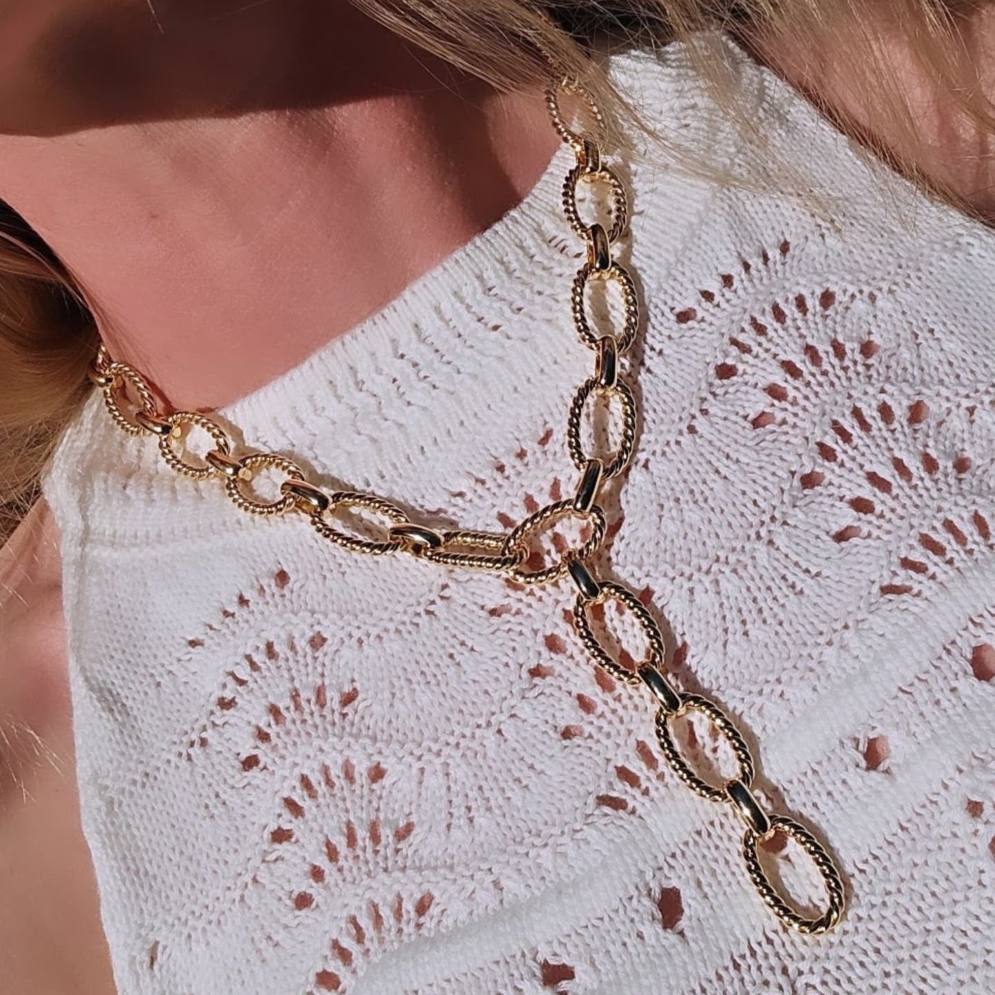 Gold chain necklace on a white lace top