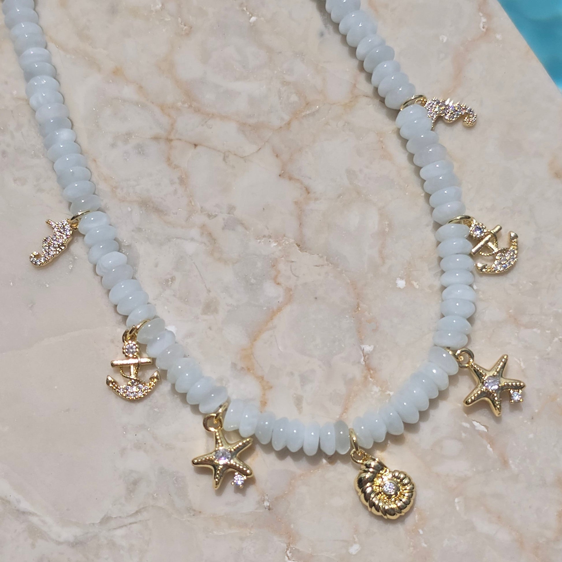 Necklace with gold charms on a marble surface